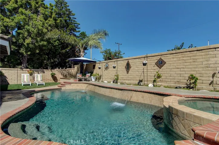 Pebble-tec pool and spa with waterfalls in backyard.