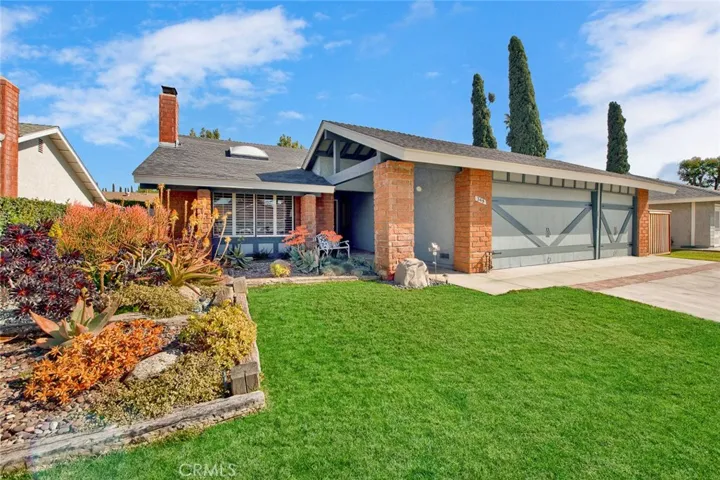 Single level ranch style home has colorful drought tolerant succulent beds and lawn area.