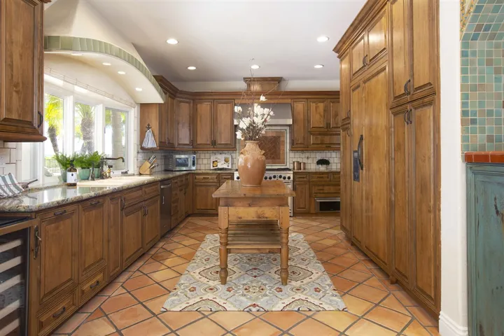 The kitchen is a chef’s dream with dark wood cabinetry that is built-to-last and splashes of colorful tile that add to the warmth to the home. Kitchenaid 8-burner gas range w/ dual-ovens