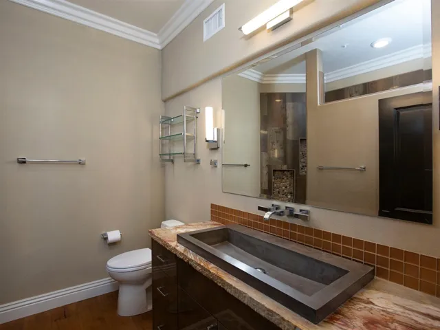 Downstairs en-suite bathroom with custom stone sink and shower with pebbled flooring
