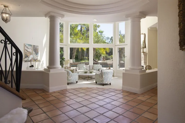 Custom wood and iron doors reveal the immense amount of natural light streaming in on the spacious foyer