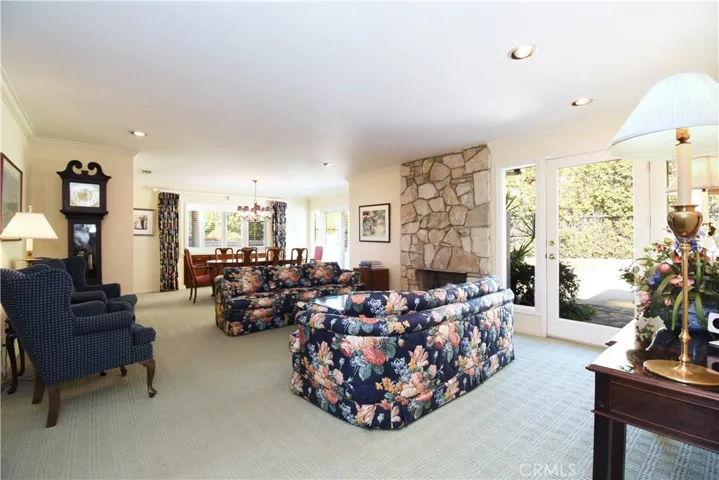 Formal living room with PV stone fireplace and 2 french doors leading to yard/pool. Recessed lighting, crown molding, grandfather clock.