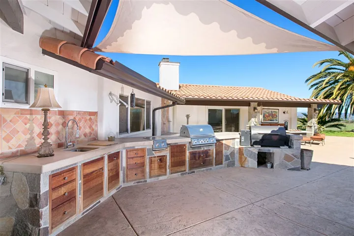 OUTDOOR KITCHEN: featuring Traeger smoker, Bull BBQ grill, 2 outboard burners and running water with smooth concrete counters.