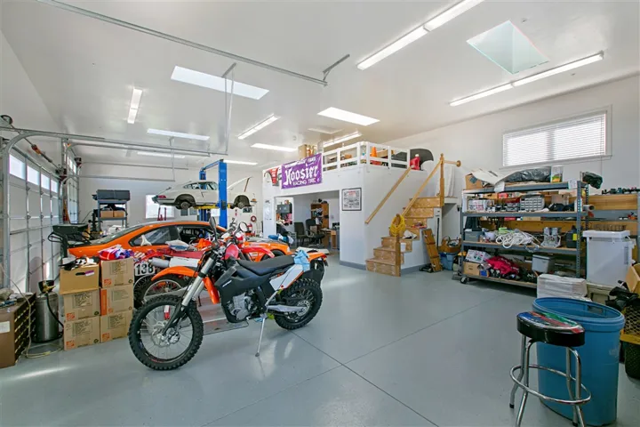 Work shop interior with Rotary brand 2 post car lift in the background. 6 tempered glass skylights, Heavy Duty wall unit AC and alarm system.  RV and trailer parking outside the shop. RV hook ups.