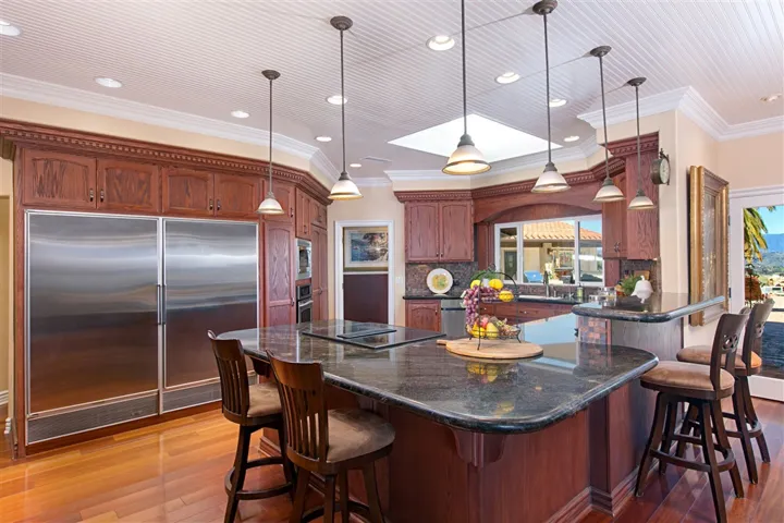 Black swirled granite counter tops, double oven with warming drawer, double sided Sub Zero refrigerator/freezer and a view of the valleys and patio entertainment area right from the kitchen sink