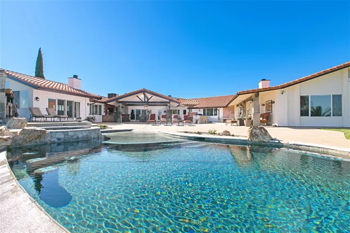 View looking over vanishing edge pool back toward portico, bar and outdoor kitchen.