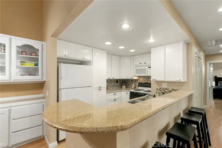 The adjacent upgraded kitchen features newer cabinets, granite counters and breakfast bar.