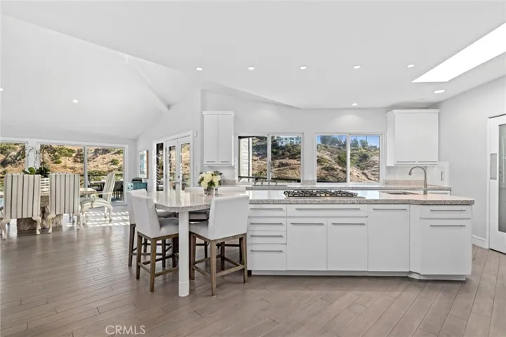 An island kitchen complements meal prep and casual get-togethers with custom white cabinetry, quartz countertops, a built-in desk, breakfast bar and walk-in pantry.
