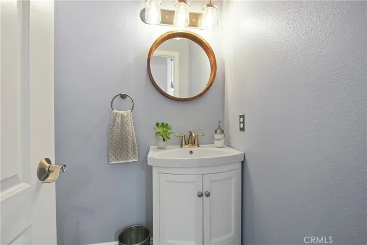 The downstairs powder room has been updated with a new vanity, stainless farmhouse style light fixture and soothing custom paint.