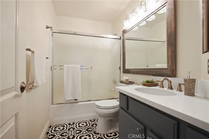 The secondary upstairs bathroom with full bath/shower features an updated vanity, mirror and designer light fixture. The beautiful flooring matches the master bathroom.
