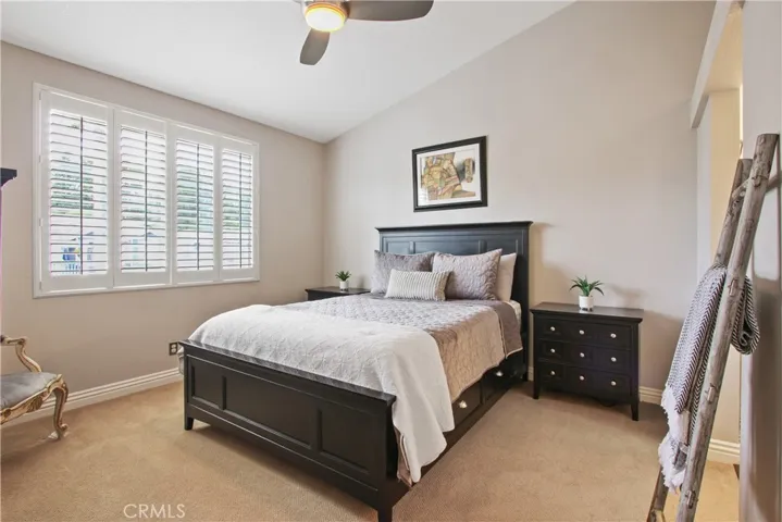 The master bedroom features a vaulted ceiling, plantation shutters, modern ceiling fan with lighting and custom paint.