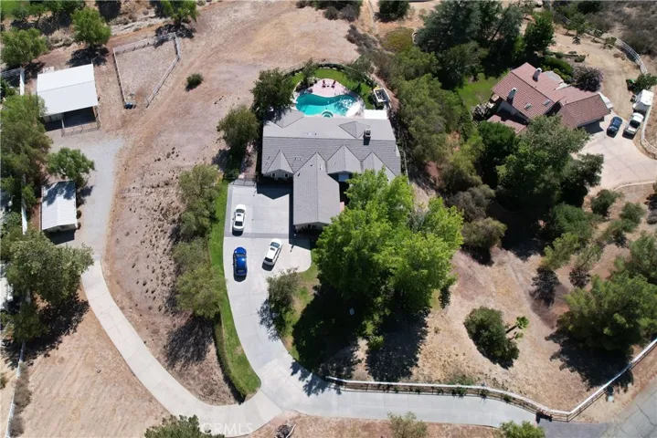 Aerial view of property showing ADU, Barn, and Corral to the left, home with pool and view to the right.