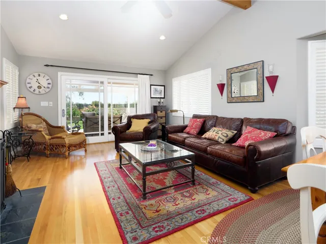 Family room with beamed ceiling, plantation shutters, and large sliding doors to patio.