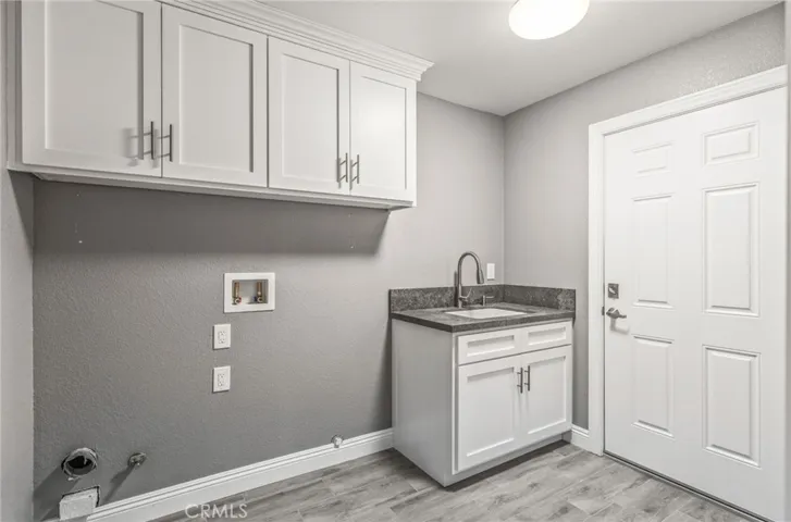 laundry room with built in sink and cabinets and access door to garage