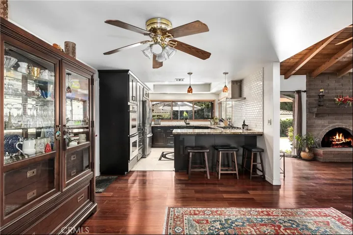 Peak of kitchen that opens to family room with fireplace and sliding glass doors.