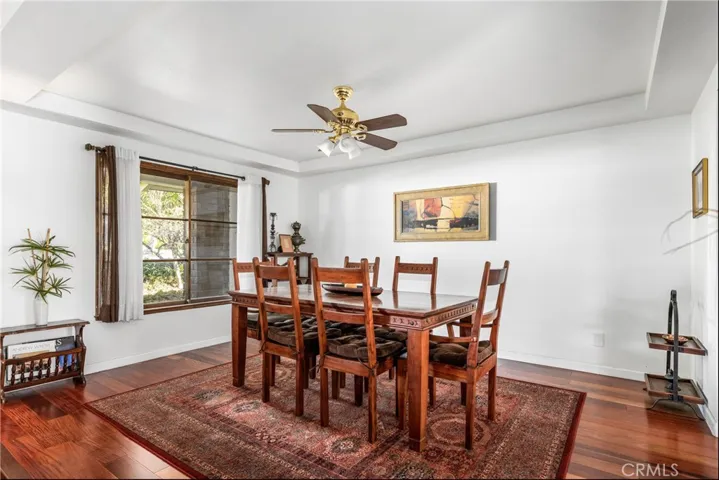 Dining room with coffered ceilings, ceiling fan and beautiful mahogany wood floors.