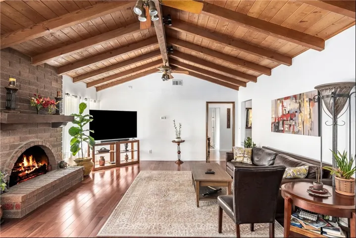 Inviting family room with high wood ceilings and beams, warm mahogany wood floors and stone fireplace.