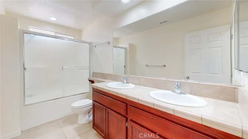 Shared hallway bath with dual vanity, large mirror and nice glass enclosed tub/shower combination