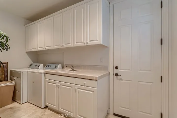 Separate laundry room with sink and storage