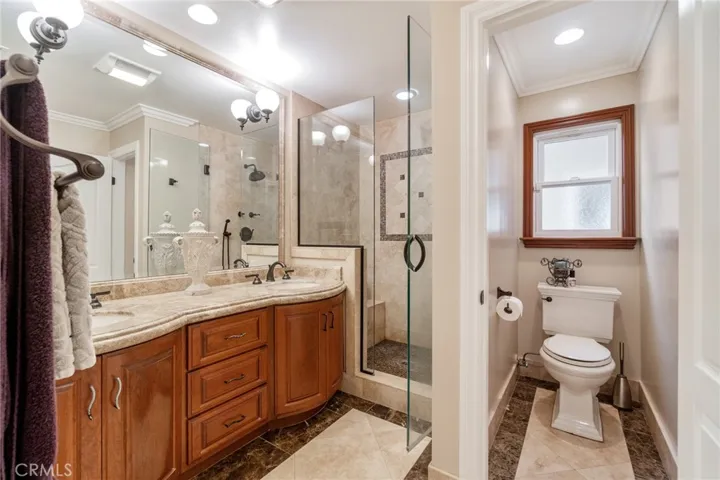 Master bath showing double sinks, stall shower and toilet with privacy door
