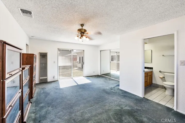 Primary bedroom with its own bathroom, and sliding door overlooking the backyard.