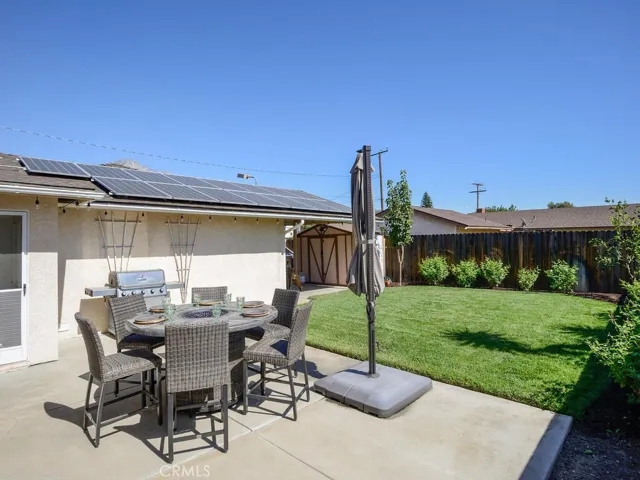 View of rear patio, storage shed and solar panels (owned and transfers at no cost to new buyer)