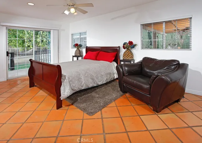 The master suite is enriched by picture windows, recessed lighting, lighted ceiling fan, ample closet space, rich terra cotta tiled floors and sliding doors that lead to a private deck and the backyard.