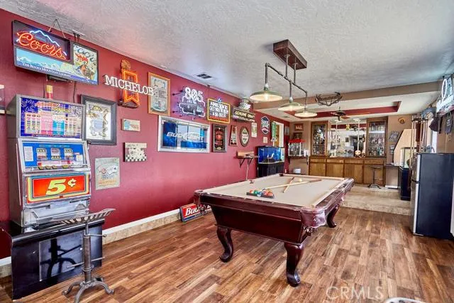 Large game room with custom, handmade vintage triple light fixture available for purchase. Upgraded flooring. Wall shelves serve as a bar top for snacks and drinks. Those are also hand made. Custom pool cue carousel on the wall that is available for purch