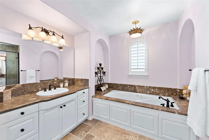 Primary bath with fresh white cabinets, make up vanity, soaking tub and separate sinks