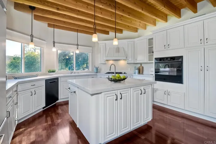 Beautifully remodeled kitchen featuring quartz counters, island w/ bar sink & lovely white cabinetry