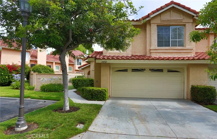 The front of the home showing the two car attached garage and driveway big enough to park in.  The walkway to the left goes through a gate to the front door.