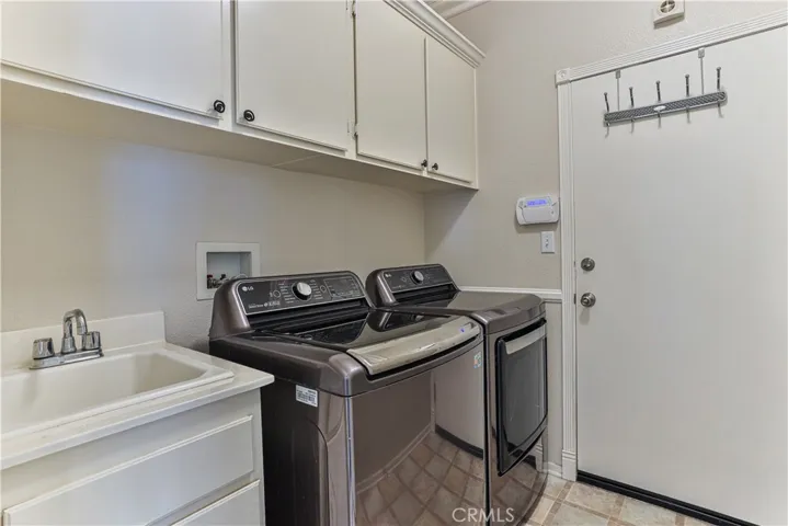 Downstairs laundry room has storage and a sink