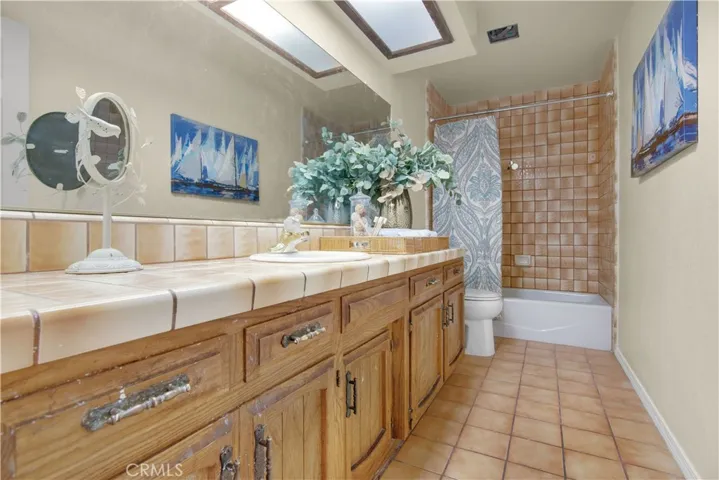 Full hall bath with tiled tub/shower, tiled counters and floors