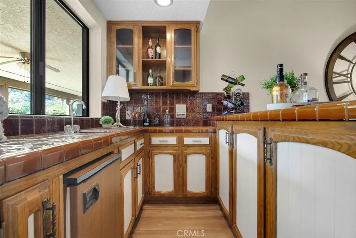 The bar area has cabinets,  a wet bar and refrigerator