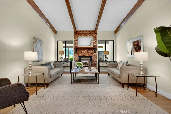 Large open living room with new laminate flooring, beamed ceilings and a bricked wood stove