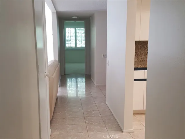 Hallway to the guest bedroom at the end with window covered with plantation shutters.