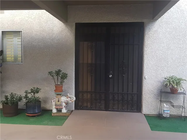 Wrought iron double screen gate leads to the double wooden entry door.