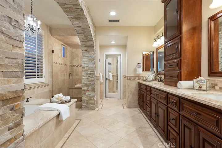 Luxurious new stone details in the primary bathroom featuring a newer jetted tub, stunning marble counters and newer furniture quality cabinetry.