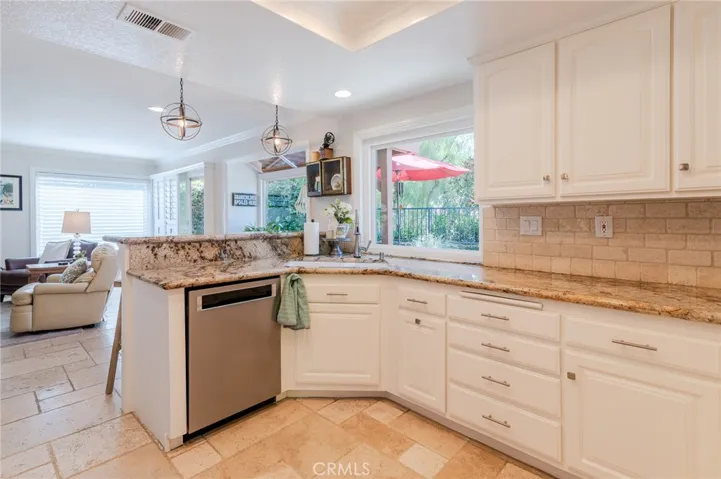 Kitchen with granite countertops and travertine backsplash.