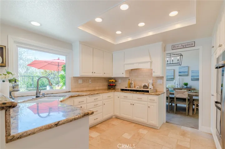 Beautiful kitchen with white cabinets and picture window looking onto the backyard.