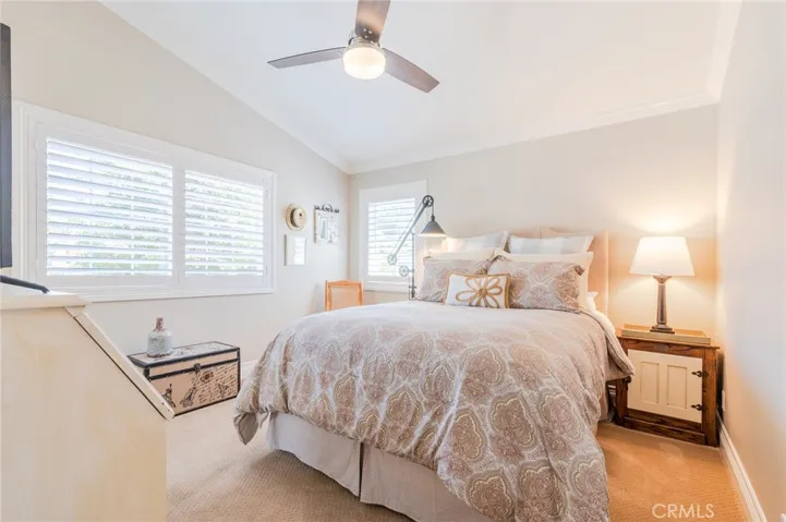 Guest bedroom located upstairs with plantation shutters and ceiling fan.