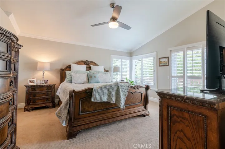 Gorgeous master bedroom with plantation shutters, ceiling fan and crown molding.
