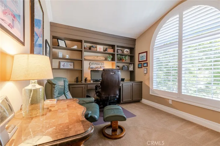 Guest bedroom located upstairs, currently being used as office with built-in and plantation shutters.