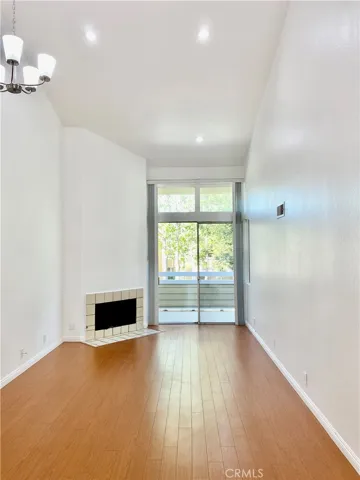 View of living room from kitchen. New paint. New recessed lights. High ceiling. Fireplace.