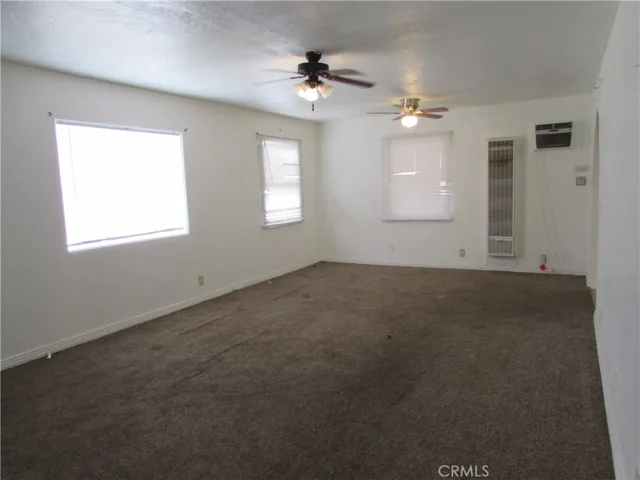 Living room has several windows to let the sun shine in.