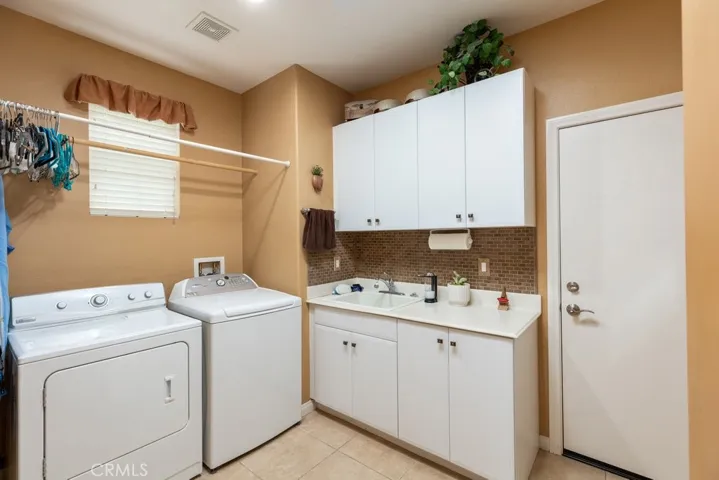Indoor laundry - upper and lower cabinets with sink and door on right leads to 2 car attached garage