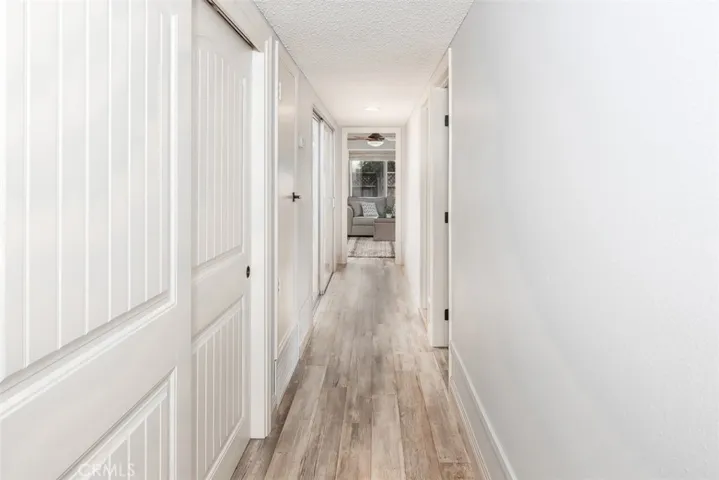 Back hallway has large linen closet on left and then door for newer furnace (2018) and slider to atrium. On right are doorways to two of the three back bedrooms.