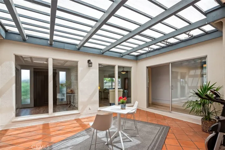 At the center of the home is this fantastic open air atrium. Standing by the kitchen slider looking out, the front door is through the floor to ceiling windows, then to right is living room and then second slider which is hallway to the secondary bedrooms. I have seen homeowners use this area for in-ground spa, tropical garden, reading room, and some have roofed in for a family room.