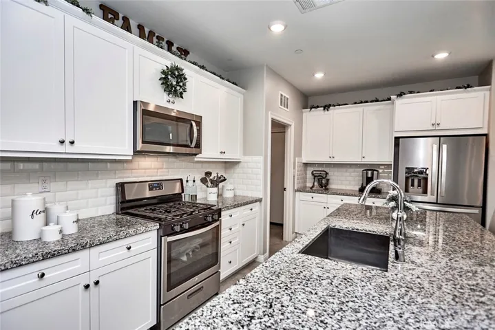 Modern Farmhouse Kitchen with Huge Island, shaker cabinets, large subway tile, stainless appliances, pantry, coffee bar, and adjacent laundry room.
