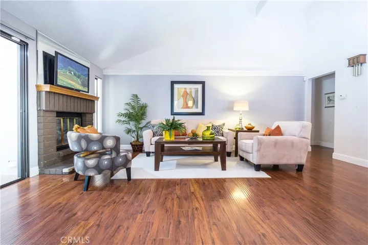 Staged family room with wide baseboards, brick fireplace and attractive wood laminate flooring.